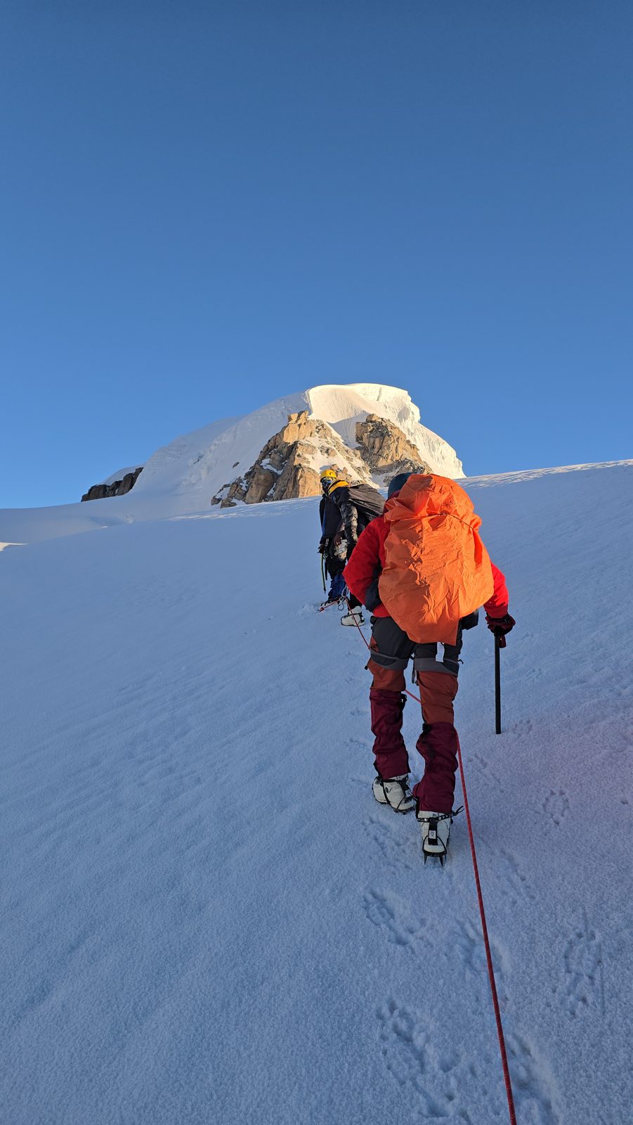 Roped sunrise ascent on a snow slope