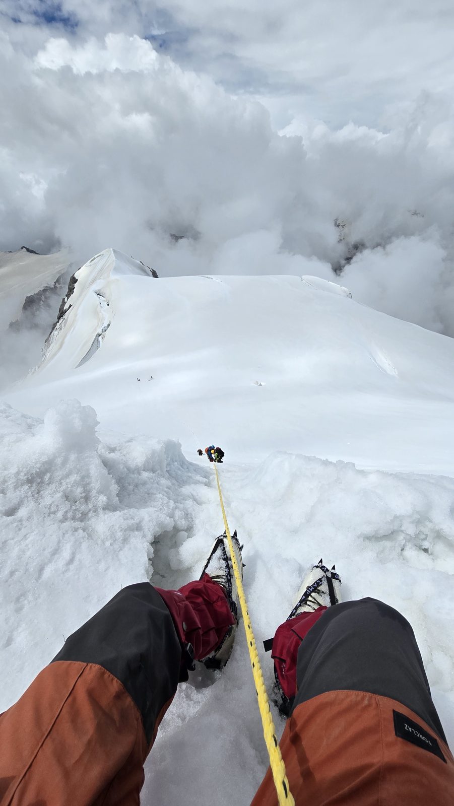 View down the ridge through clouds mid-climb